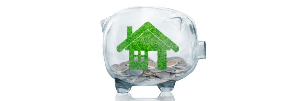 home savings concept with grass growing in shape of house inside transparent piggy bank