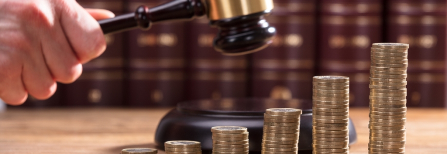 Man about to hit his gavel with gold coins piled in the front