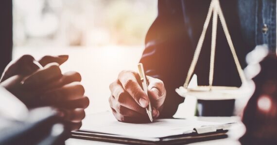 Two people discussing a contract in front of them with the legal scales in the background