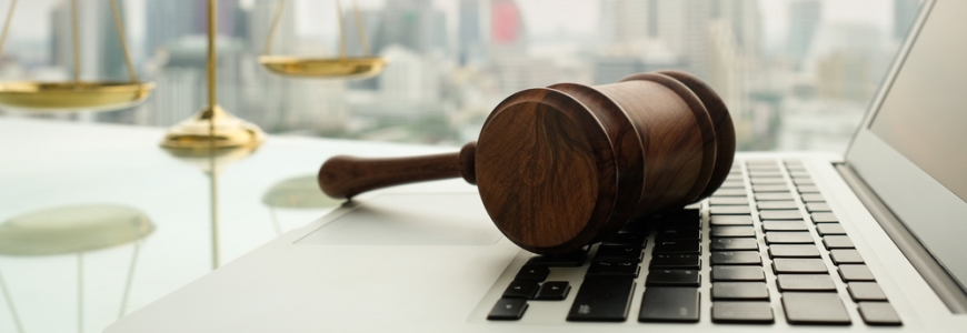 Legal weights in background with a gavel resting on a laptop