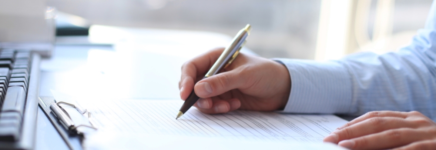 Man in work shirt filling out a questionnaire on a desk