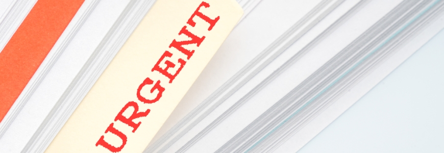 Pile of paper with a file tag sticking out with the word URGENT written in red on it