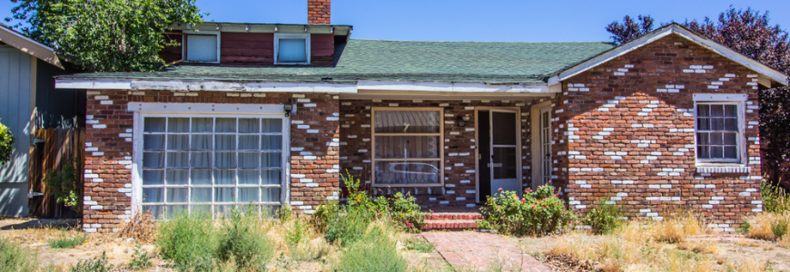 Abandoned Brick Home With Overgrown Front Yard