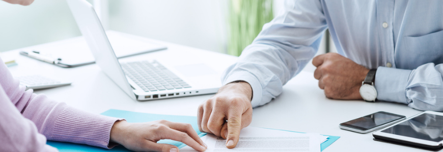 A man explaining terms of a contract to a woman at a desk