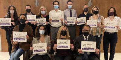 Colleagues holding up motivational placards in support of International Women's Day