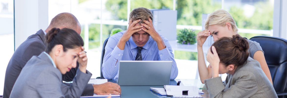 Business team looking down with head in hands looking very upset.