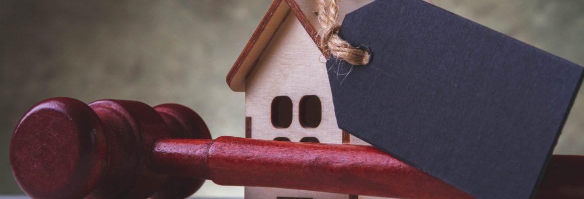 A cardboard house with a price tag on it and in front of it a gavel.