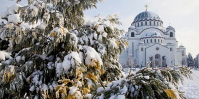 Snow covered tree branches and the St Sava cathedral in Belgrade in background