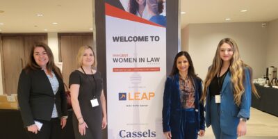 Four firm members attending Canadian Lawyer - Women in Law Summit. Standing around the pull up banner for the event.