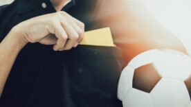 Closeup of soccer referee hand holding yellow card punishment in the stadium during match close up