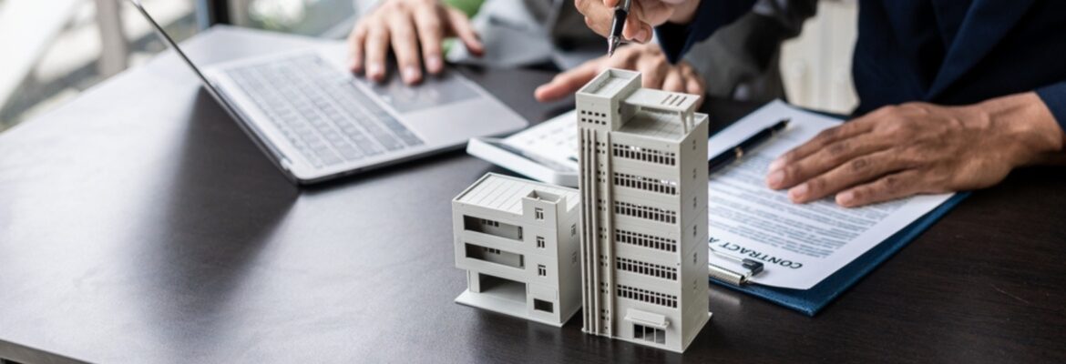 Businessman holding model small building house with property insurance at table in home sales office