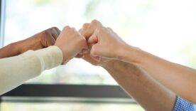 Group of young business casual adults put their hands up and fists pumping gesture.