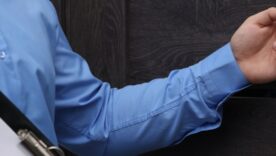 Salesman with clipboard knocking on wooden door, closeup