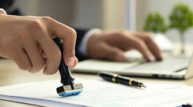 Businessman Hand Stamping With Approved Stamp On Document At Desk. validates and manages business documents and agreements.