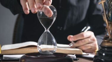 Judge's hand showing hourglass in a courtroom.